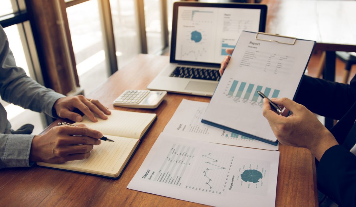 Two business partnership coworkers analysis strategy with discussing a financial planning graph and company budget during a budget meeting in office room.