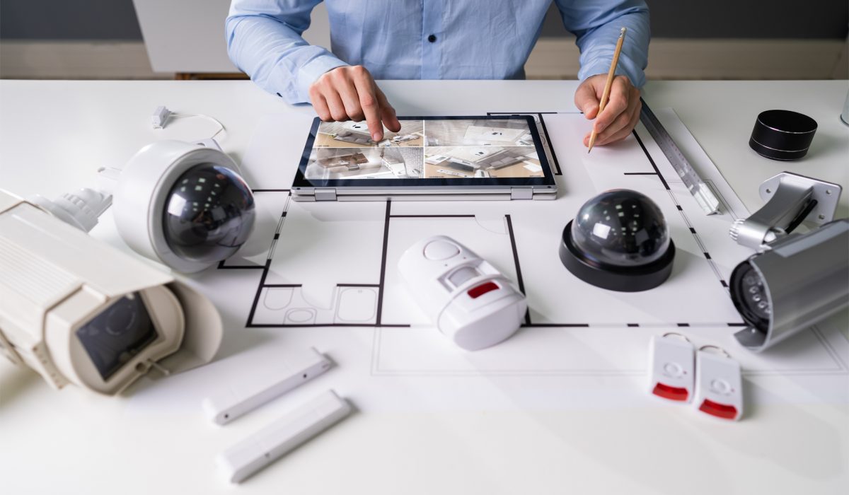 Close-up Of A Person Watching Footage On Digital Tablet With Security Equipment On Blueprint